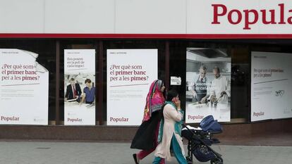 Unas mujeres pasan ante una oficina del Banco Popular.
