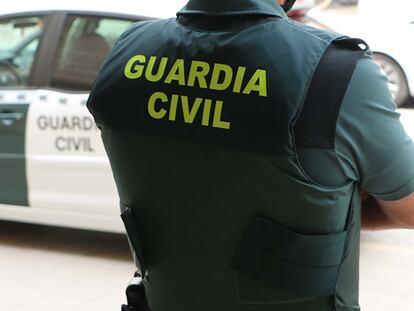 Un agente de la Guardia Civil, de espaldas, junto a un vehículo oficial.